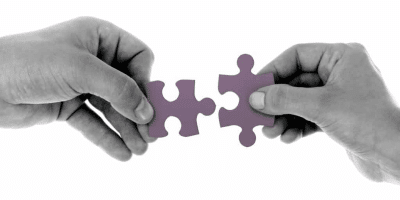 Two hands joining together puzzle pieces