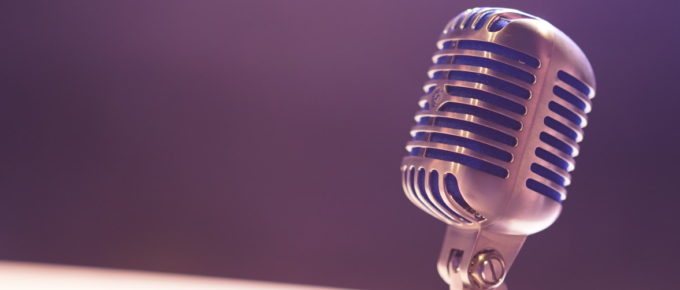Closeup on an old style silver microphone with a purple background
